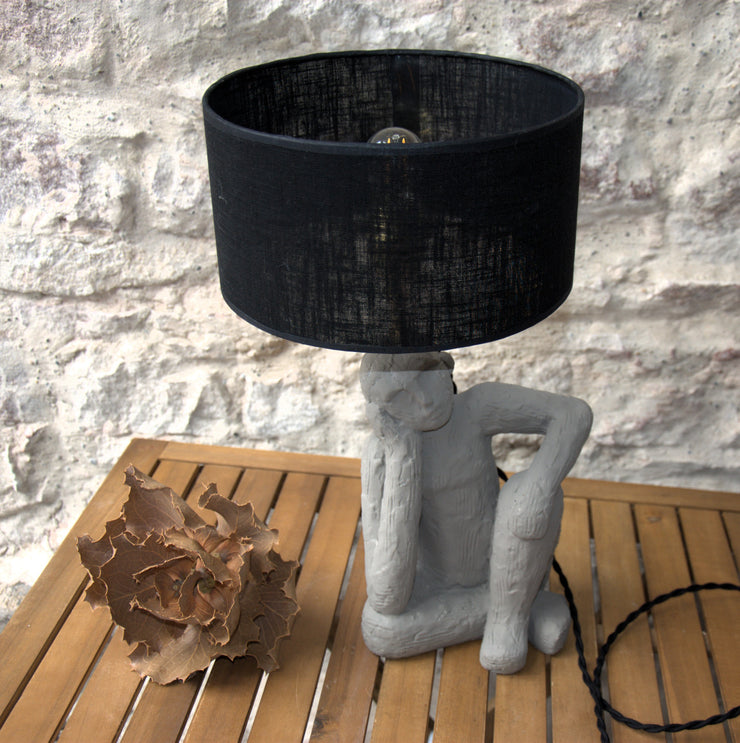 Lampe à poser Le Penseur, sculpture figurative béton, abat-jour lin noir.