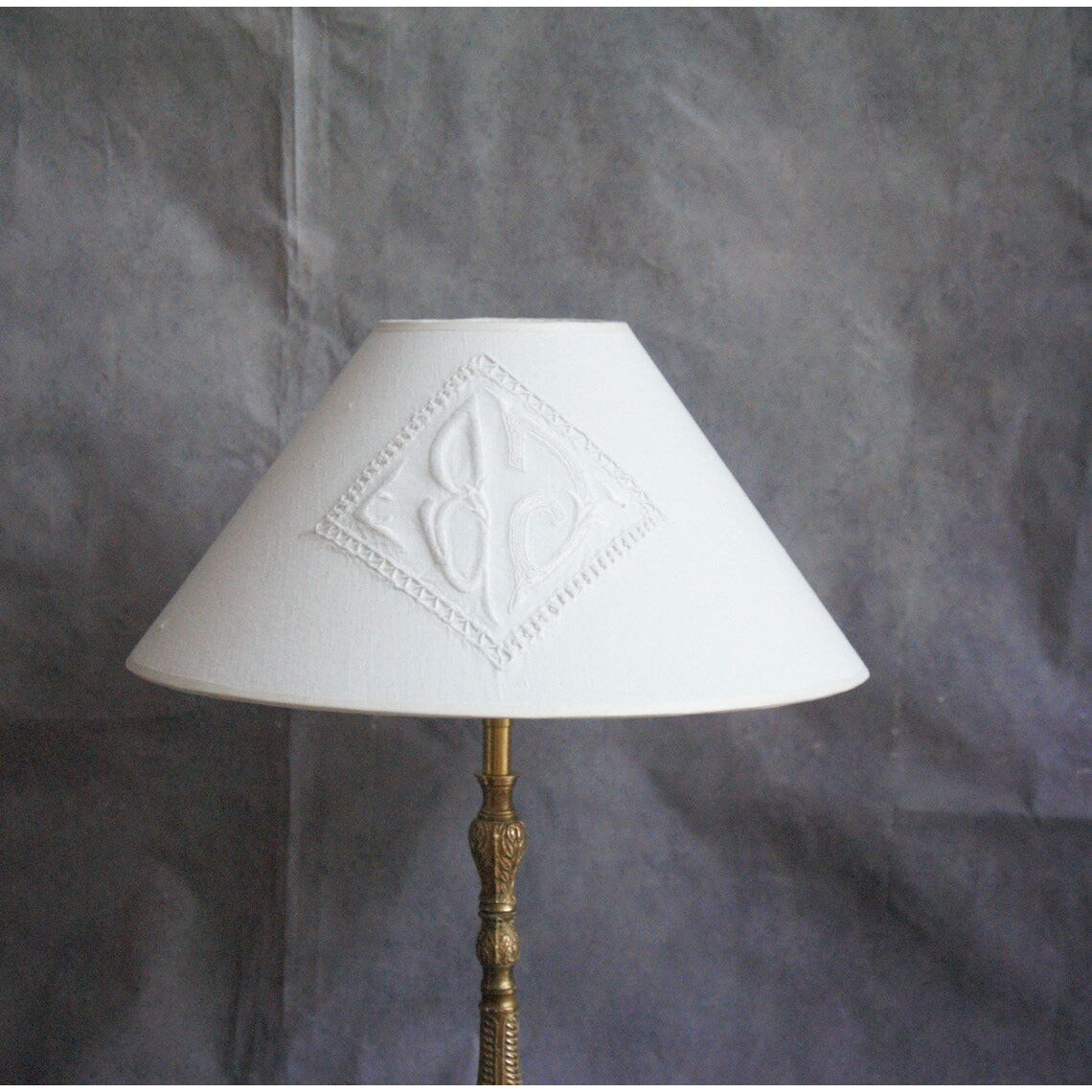 Lampe à poser en bronze , ancien pique cierge avec abat-jour en coton monogrammé.