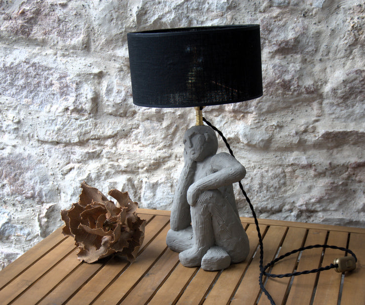 Lampe à poser Le Penseur, sculpture figurative béton, abat-jour lin noir.