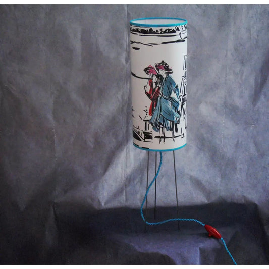 Lampe à poser abat-jour cylindrique sue trépied, papier peint Manuel Canovas.